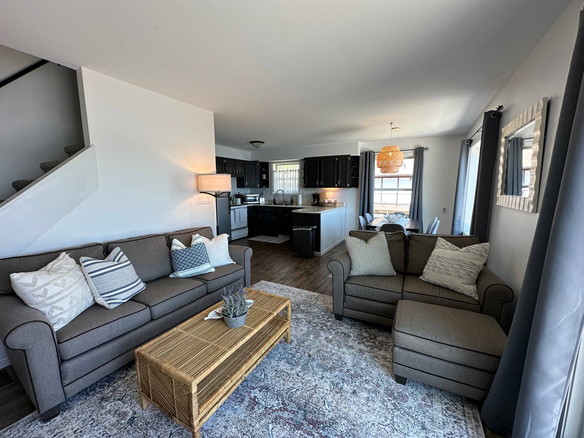 Open-concept living room at Oscoda Lakehouse with two sofas, rattan coffee table and lake-facing windows
