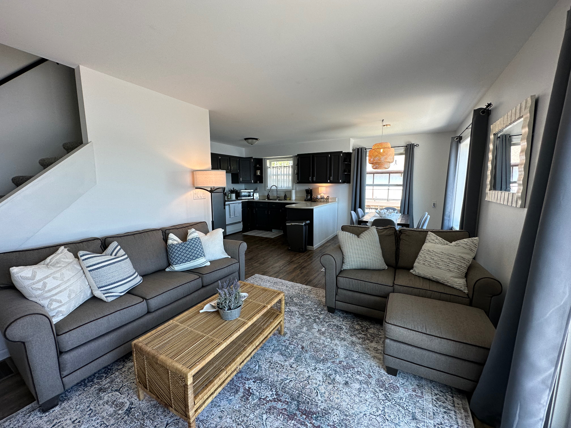 Open-concept living room at Oscoda Lake House with two sofas, rattan coffee table and lake-facing windows