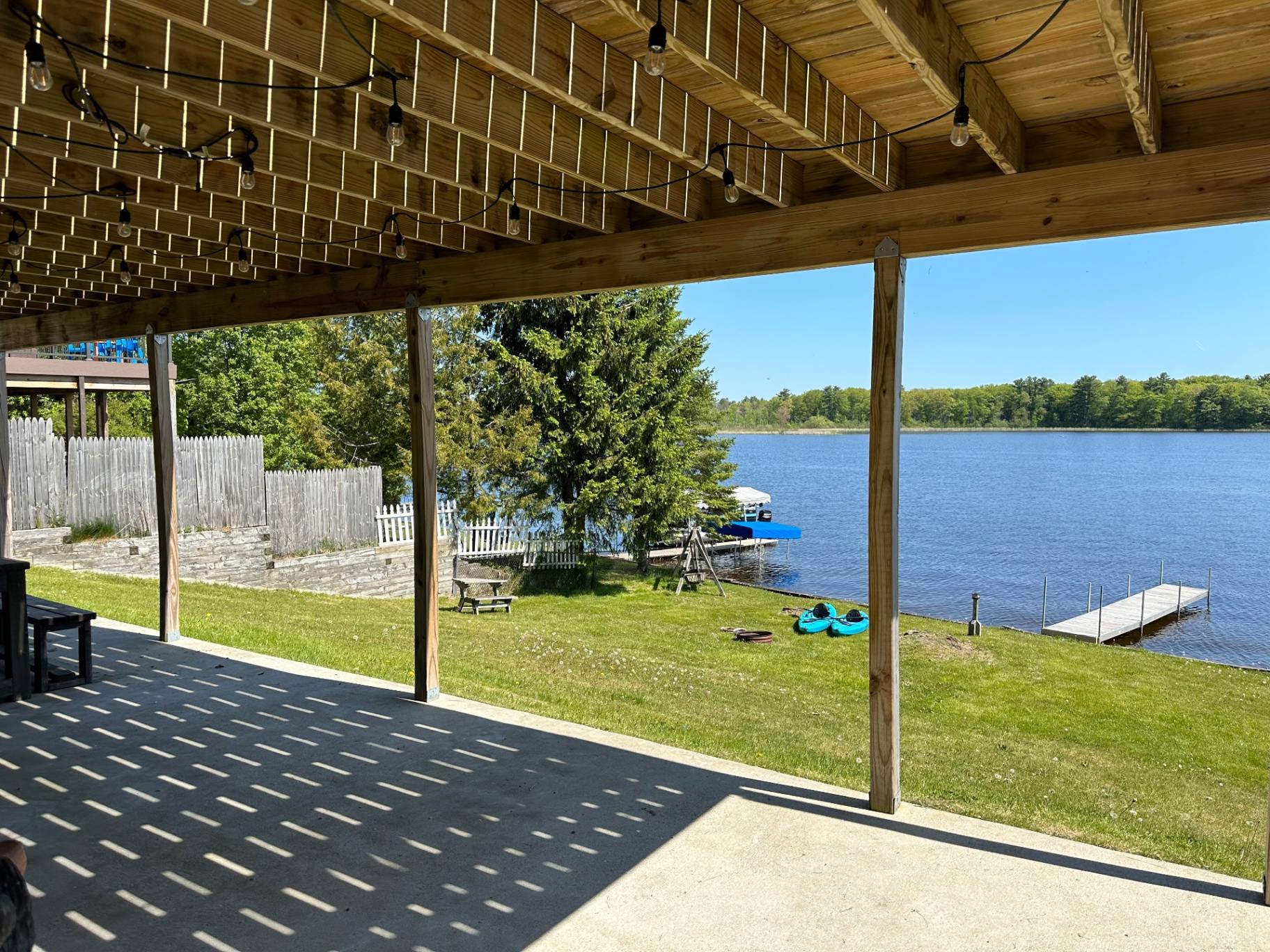 View of Van Etten Lake and the fire pit from the covered porch at Oscoda Lakehouse