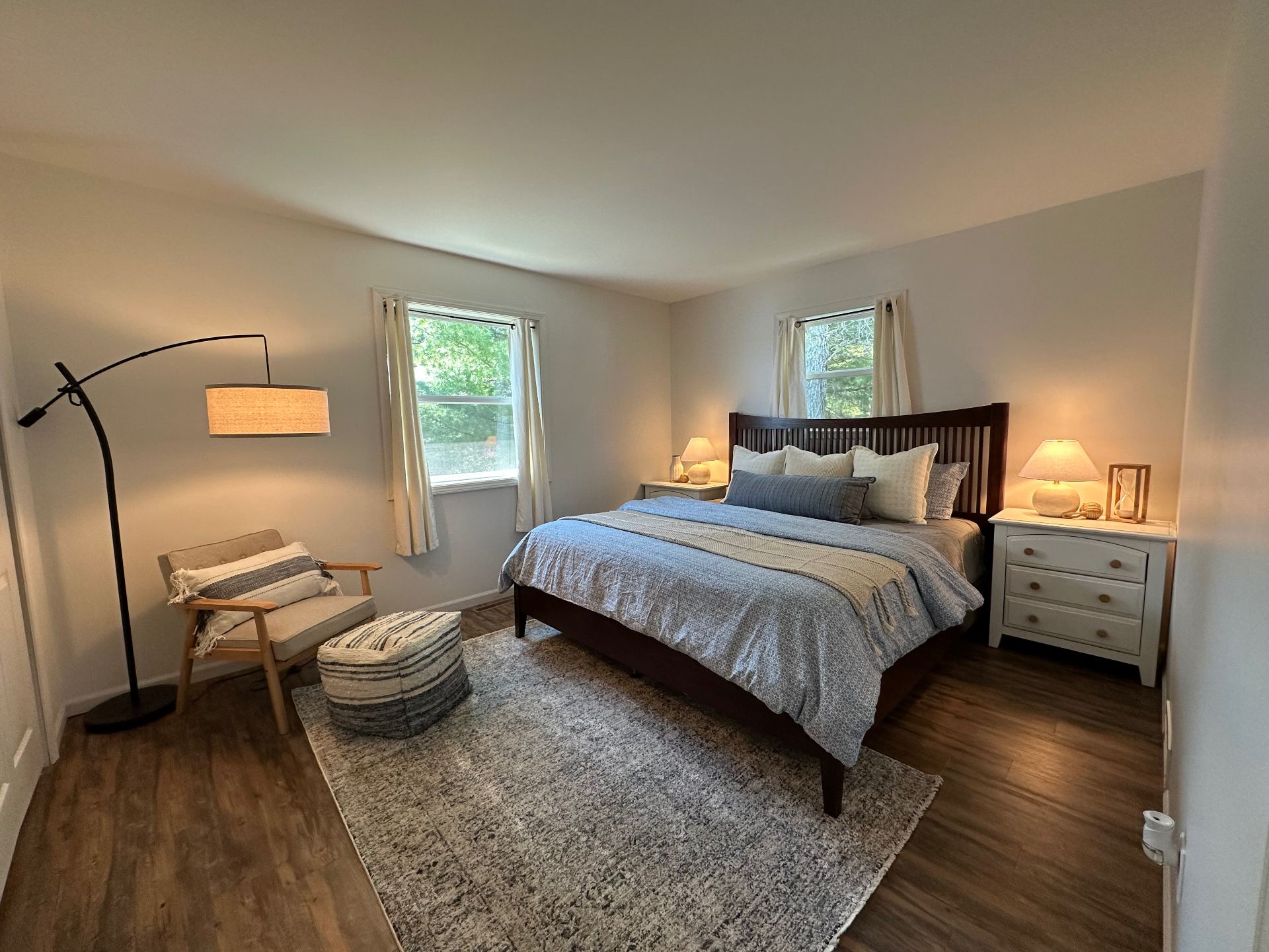 Primary bedroom at Oscoda Lakehouse with layered neutral bedding and lounge chair